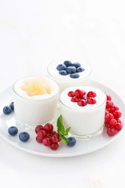 Natural yogurt with fresh berries in glass jars on white table — Stock Photo, Image
