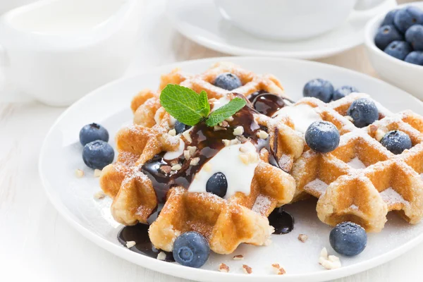Waffles with blueberries, cream and chocolate sauce, close-up — Stock Photo, Image