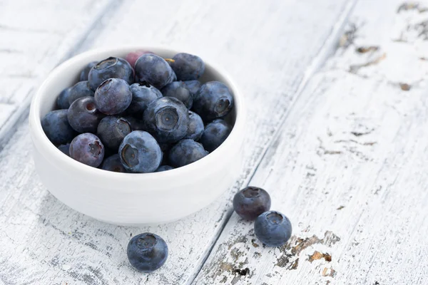 Schüssel mit frischen Blaubeeren auf weißem Holzhintergrund — Stockfoto