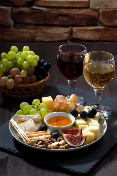 Placa con snacks delicatessen y vino sobre fondo oscuro, vertical —  Fotos de Stock