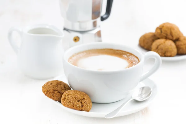 Tasse Cappuccino und Makronen auf weißem Tisch, selektiver Fokus — Stockfoto