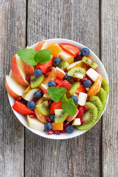 Insalata di frutta e bacche su fondo di legno, verticale, vista dall'alto — Foto Stock