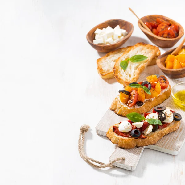 Bruschettas with tomatoes and mozzarella on wooden board — Stock Photo, Image