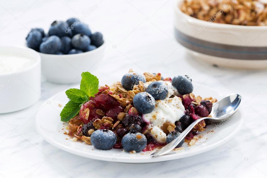 berry crumble with oat flakes, cream and blueberries
