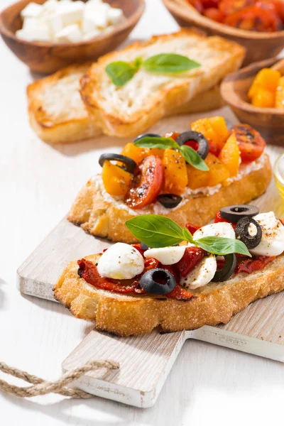 Bruschettas with tomatoes and mozzarella on wooden board — Stock Photo, Image