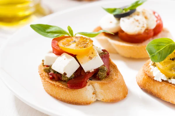 Bruschettas with tomatoes and mozzarella on plate, closeup — Stock Photo, Image