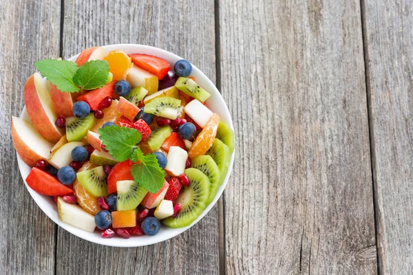 Insalata di frutta e bacche su sfondo di legno, vista dall'alto — Foto Stock