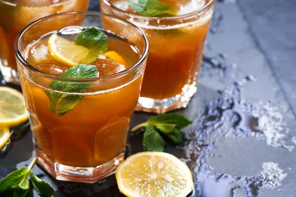 Té helado con menta y limón en vasos sobre fondo oscuro — Foto de Stock