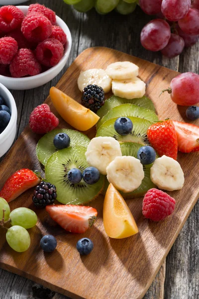 Ingredientes para salada de frutas em tábua de madeira, vertical, close-up — Fotografia de Stock