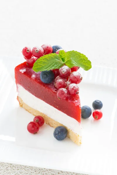 Pedaço de delicioso cheesecake com geleia de baga em um prato branco — Fotografia de Stock