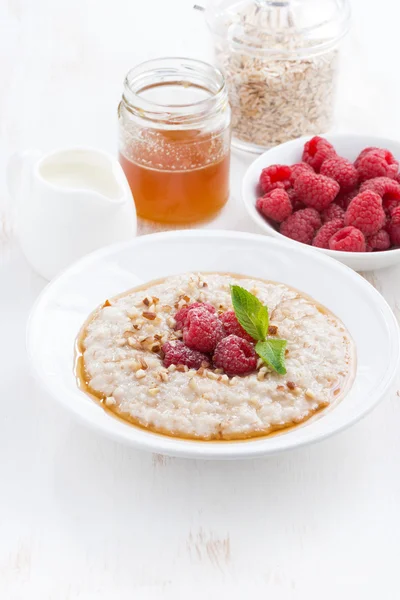 Plate of oatmeal with fresh raspberries and honey, vertical — Stock Photo, Image