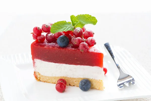 Un trozo de delicioso pastel de queso con gelatina de bayas en un plato blanco — Foto de Stock