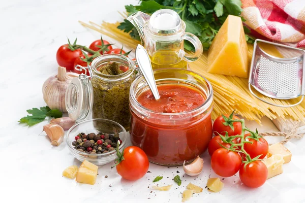 Tomatensaus, pesto en ingrediënten voor de pasta op een witte tafel — Stockfoto