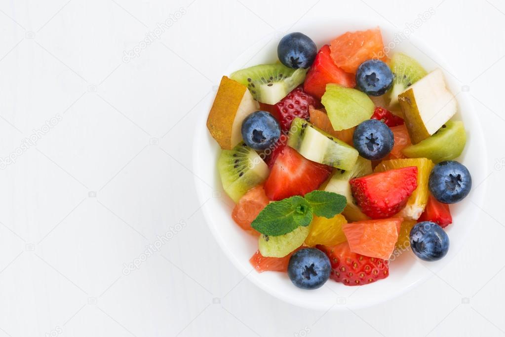 Delicious fruit salad in a bowl, closeup, top view