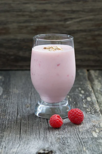 Milkshake with raspberries on a wooden background, vertical — Stock Photo, Image