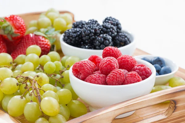 Bandeja de madera con bayas frescas y uvas, primer plano — Foto de Stock