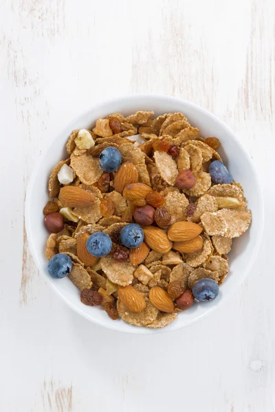 bowl of cereals flakes, blueberries and nuts, vertical, top view