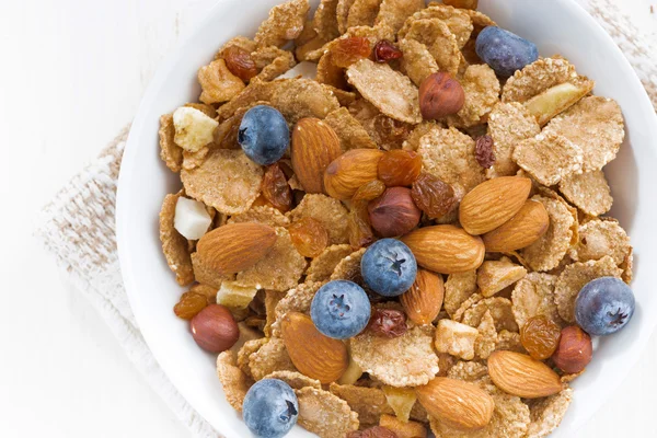 Tazón de cereales copos, arándanos y frutos secos en la mesa blanca — Foto de Stock