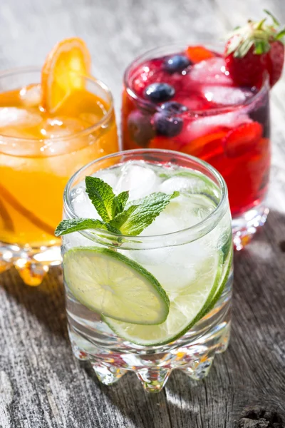 Assortment of iced fruit drinks on wooden background, vertical — Stock Photo, Image