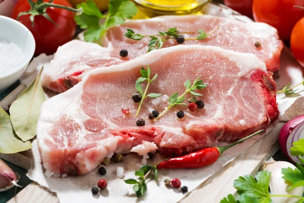 Two pieces of pork on a cutting board and fresh foods, closeup — Stock Photo, Image