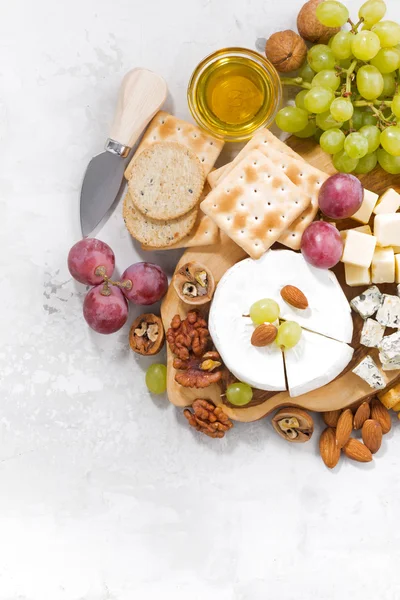 Camembert, üzüm ve beyaz bir arka plan, dikey snacks — Stok fotoğraf