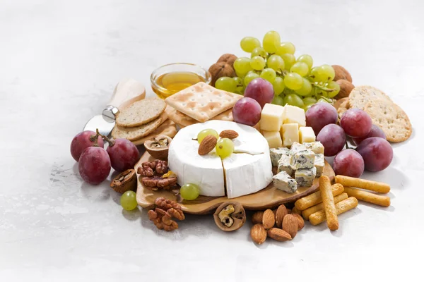 Camembert, uvas e lanches sobre fundo branco — Fotografia de Stock