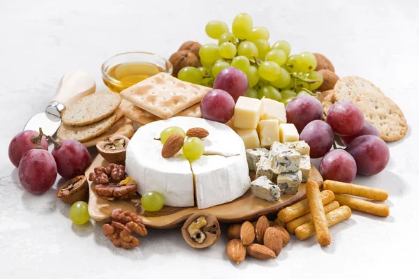 Camembert, uvas e lanches sobre um fundo branco, close-up — Fotografia de Stock