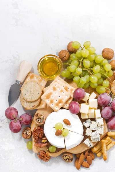 Camembert, winogron i przekąski na stół biały, pionowe — Zdjęcie stockowe