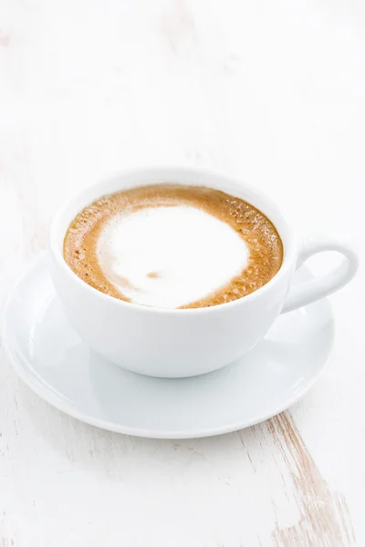 Šálek cappuccino na bílý dřevěný stůl, vertikální — Stock fotografie