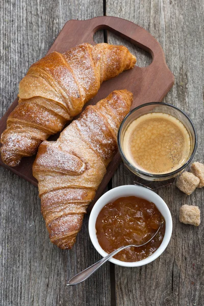 Croissants, Kaffee und Orangenmarmelade auf Holzgrund — Stockfoto