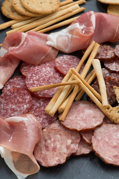Snack di carne assortiti, salsicce su una lavagna, verticale — Foto Stock