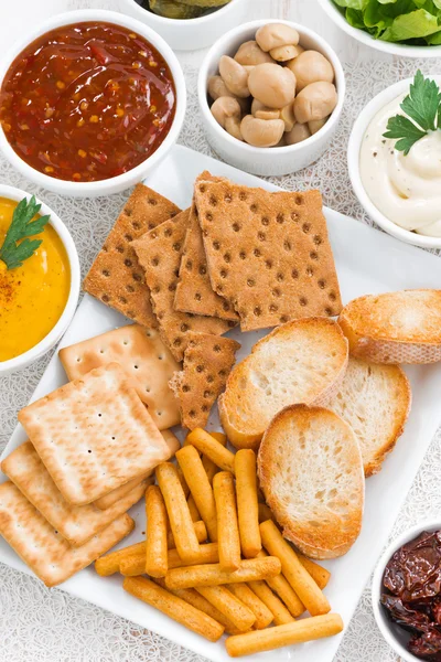 Assortment breads, crackers and sauces, closeup top view — Stock Photo, Image