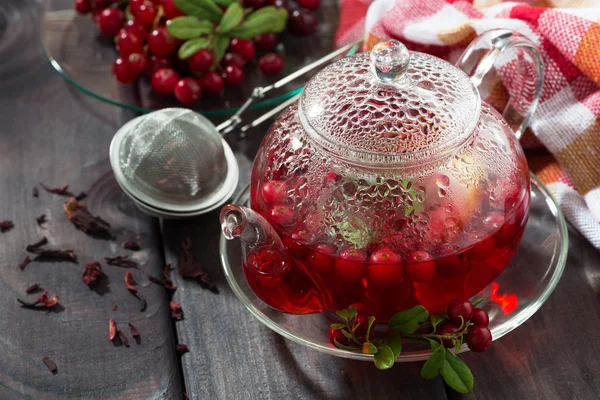 Berry tea in glass teapot on dark wooden table — Stock Photo, Image