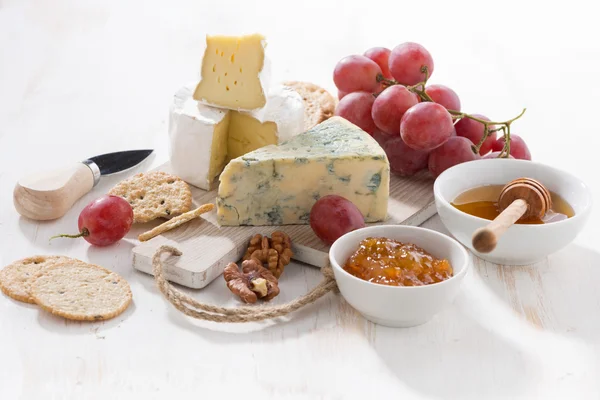 Schimmelkäse, Obst und Snacks auf einem weißen Holztisch — Stockfoto