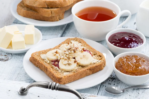 Toast with peanut butter and banana, fresh black tea — Stock Photo, Image