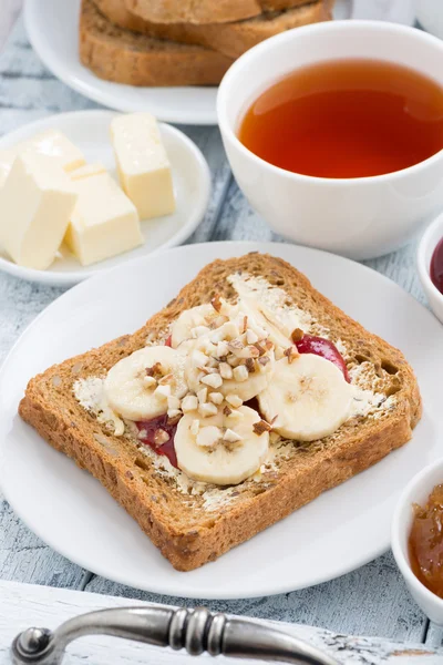Toast with peanut butter and banana, fresh black tea, closeup — Stock Photo, Image