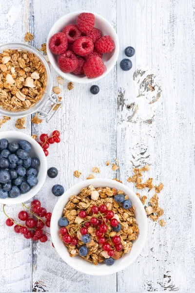 Granola y bayas frescas sobre fondo de madera blanca, vertical — Foto de Stock