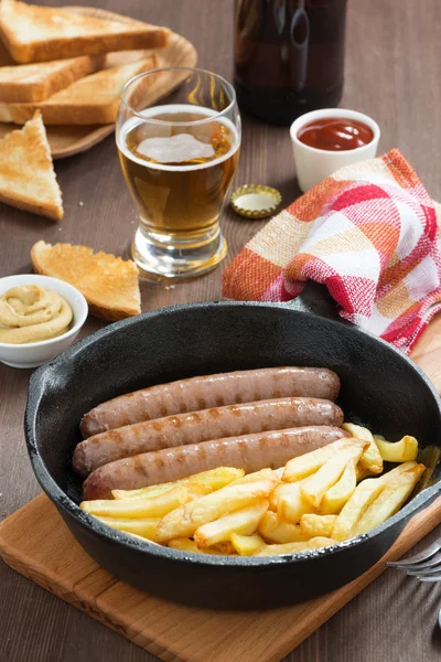 Обед с сосисками на гриле, картошкой фри, тостами и пивом — стоковое фото