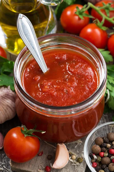 Tomatensaus in een glazen pot en ingrediënten, verticaal, close-up — Stockfoto