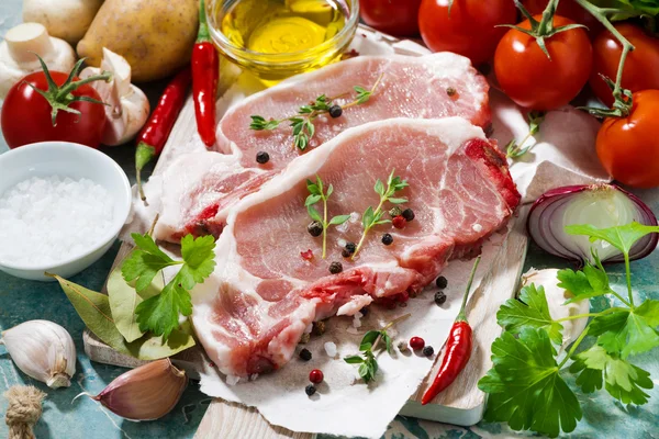 Two pieces of pork on a cutting board and fresh ingredients — Stock Photo, Image