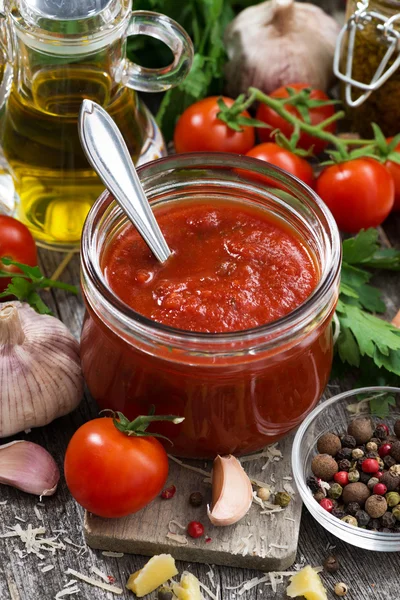 Salsa di pomodoro in un barattolo di vetro e ingredienti freschi, verticale — Foto Stock