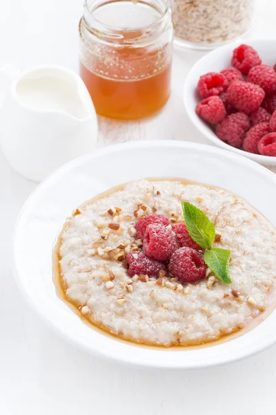 Plate of oatmeal with fresh raspberries and honey, vertical — Stock Photo, Image