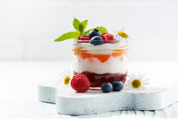 Dessert with jam, cream and fresh fruit in a glass jar — Stock Photo, Image