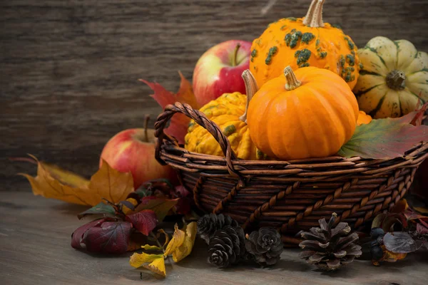 Seasonal pumpkins and apples in the basket on wooden table — Stock Photo, Image