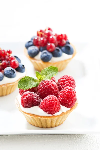Mini cakes with cream and berries, vertical — Stock Photo, Image