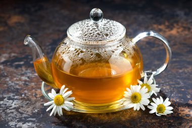 koyu arka plan üzerinde cam çaydanlık sıcak çay papatya