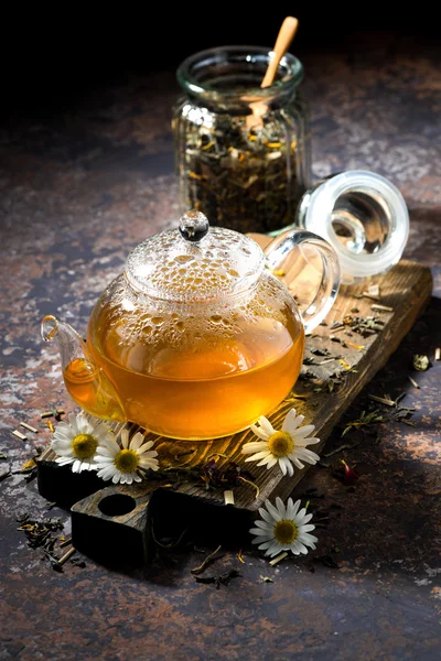 Chá de camomila em um bule de vidro no fundo escuro — Fotografia de Stock