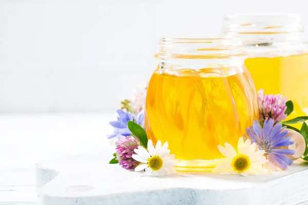 jars with fresh flower honey and white background