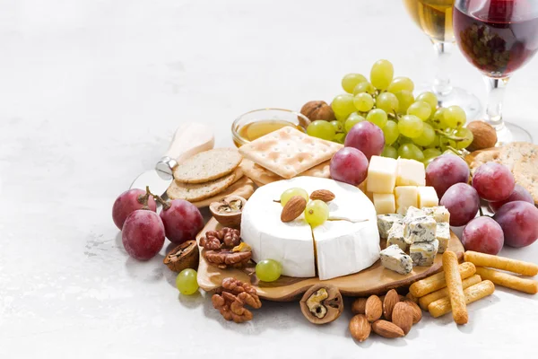 Camembert, uvas, vinho e lanches em uma mesa branca — Fotografia de Stock