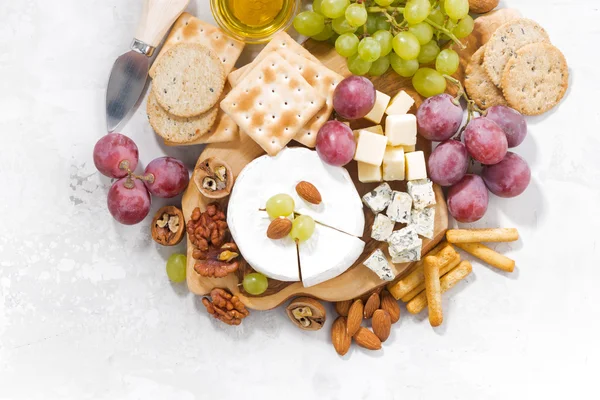 Camembert, Trauben und Snacks auf einem weißen Tisch — Stockfoto